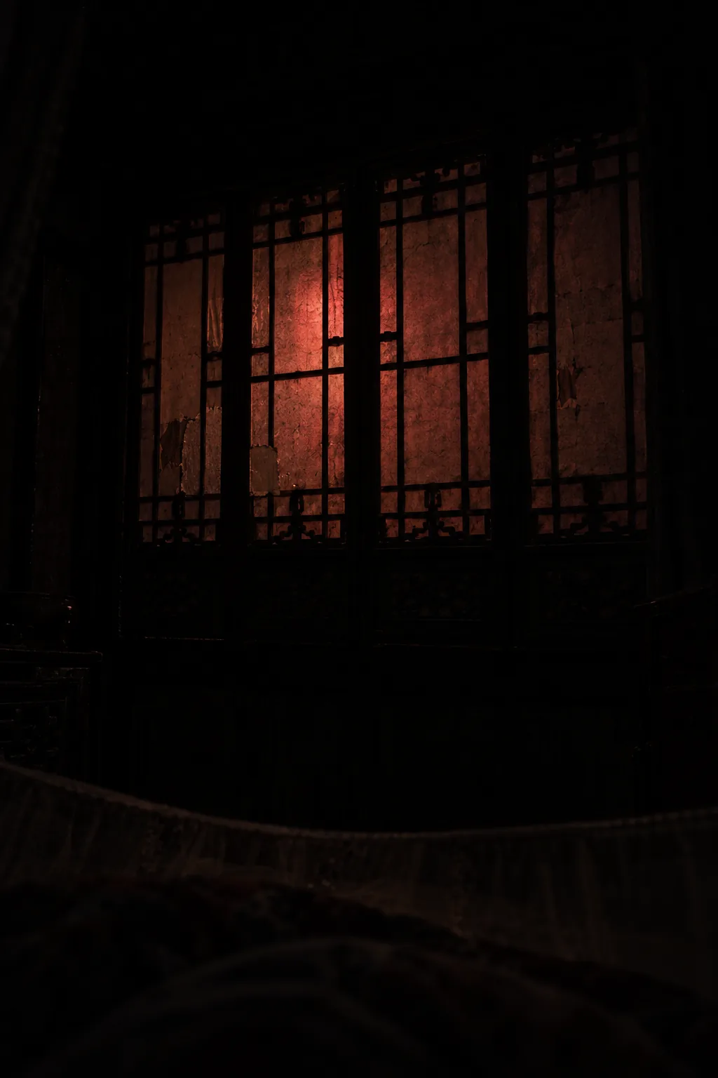 A lattice window lit with a muted red glow